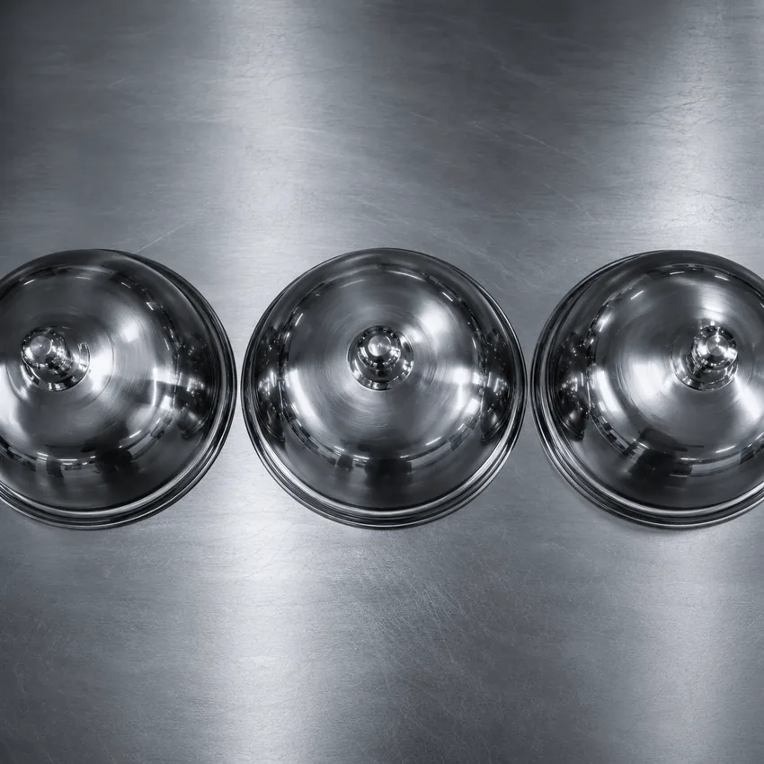Cloches de service en inox alignées sur un plan de travail