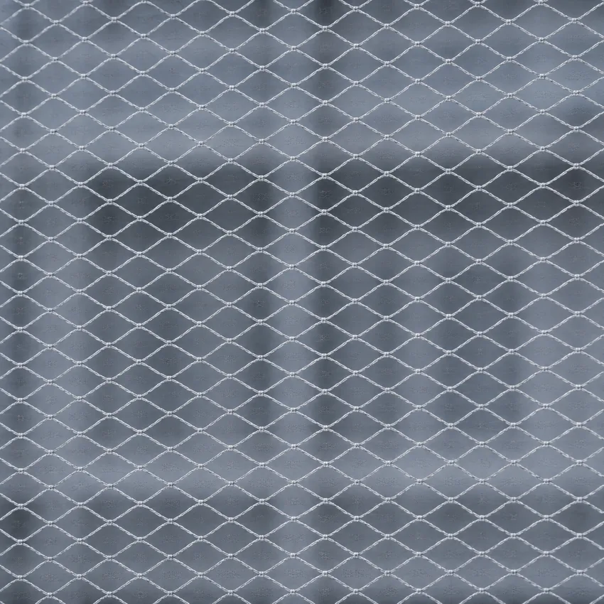 Maille d'un filet de chantier en gros plan, bâtiment devinable derrière