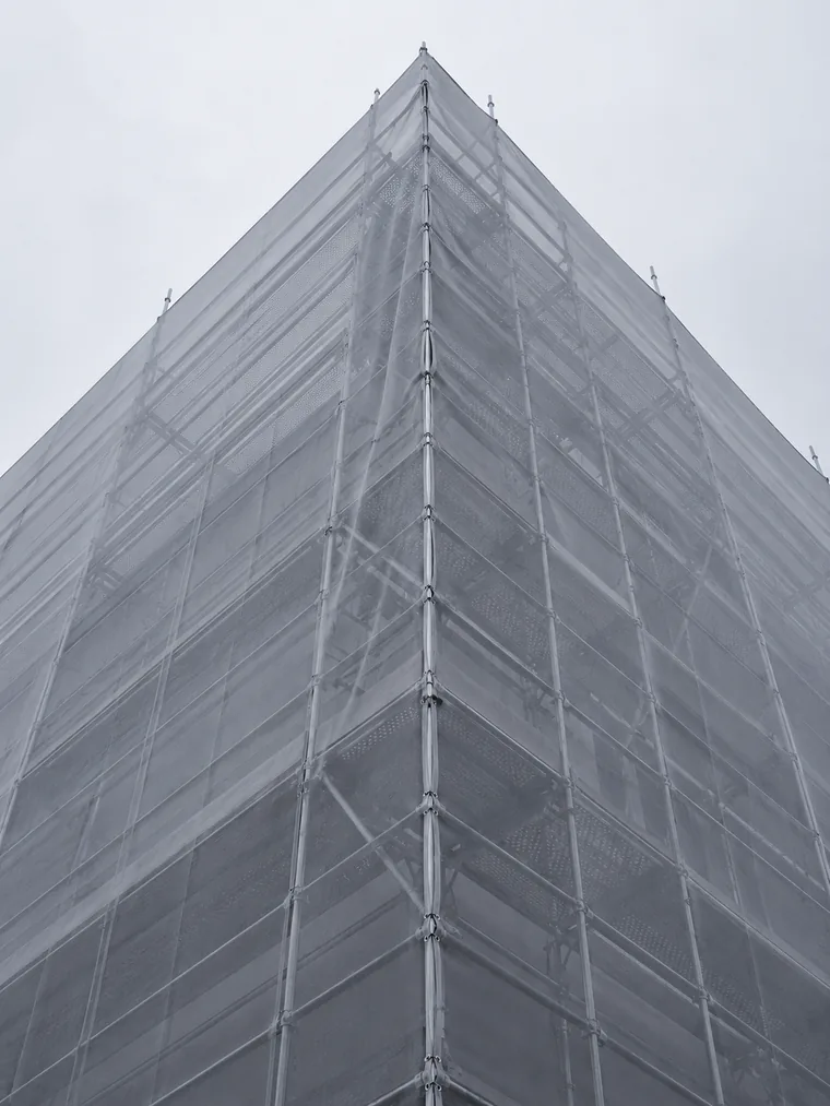 Angle d'échafaudage vu de bas en haut à travers un filet de chantier